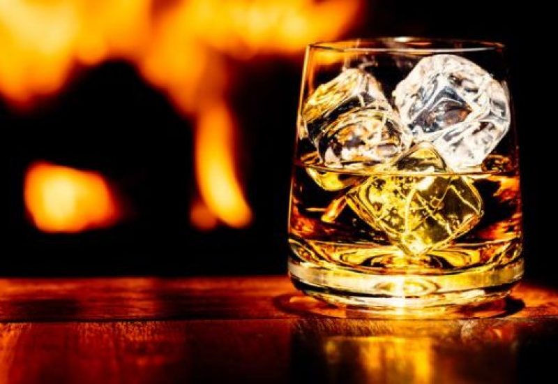 Whisky on table with flame of wood burning stove