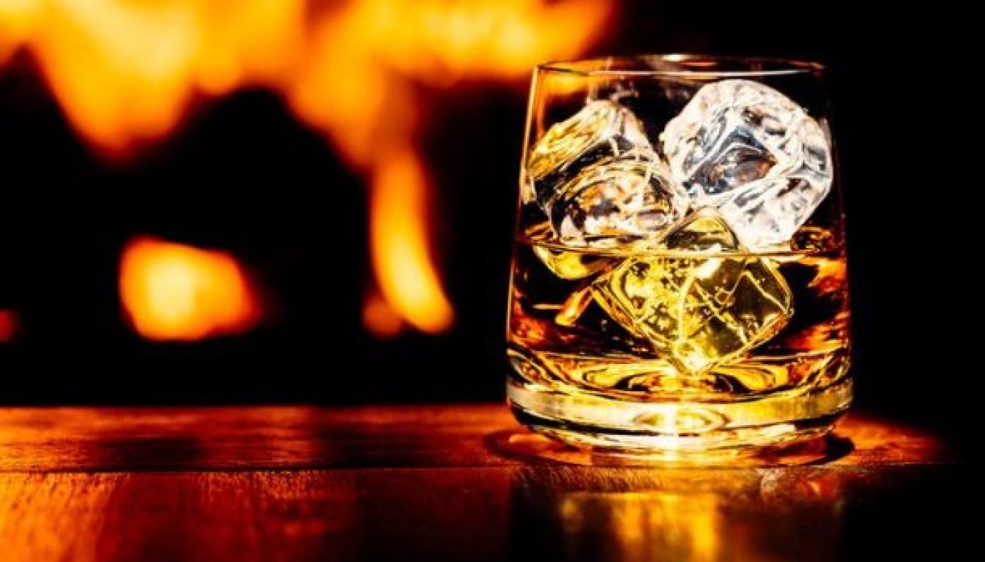 Whisky on table with flame of wood burning stove