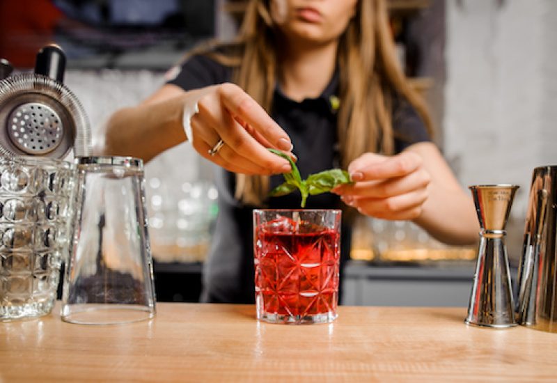 blonde barmaid adding to the cocktail mint leaves
