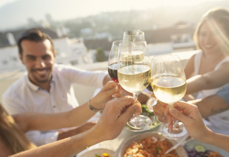 Group of friends having a meal outdoors. They are celebrating with a toast using wine.