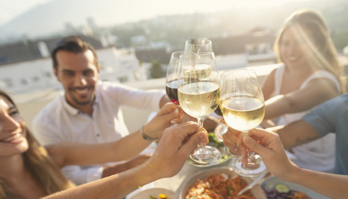 Group of friends having a meal outdoors. They are celebrating with a toast using wine.