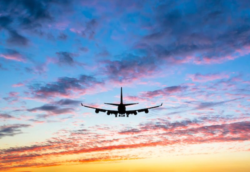 Colorful bright sunset with flying airplane silhouette
