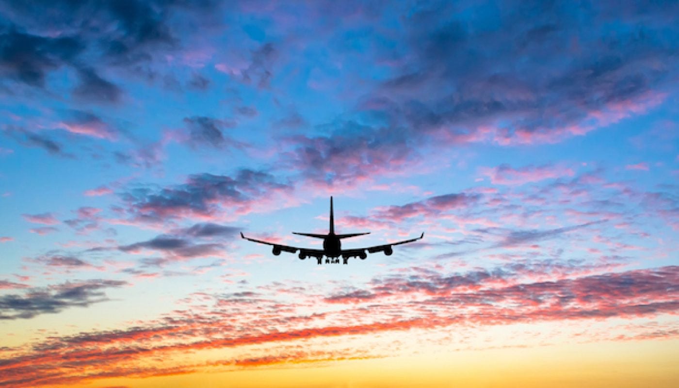Colorful bright sunset with flying airplane silhouette