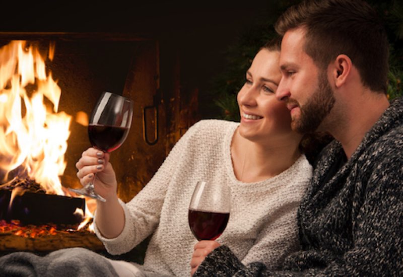 Couple with glass of wine at fireplace