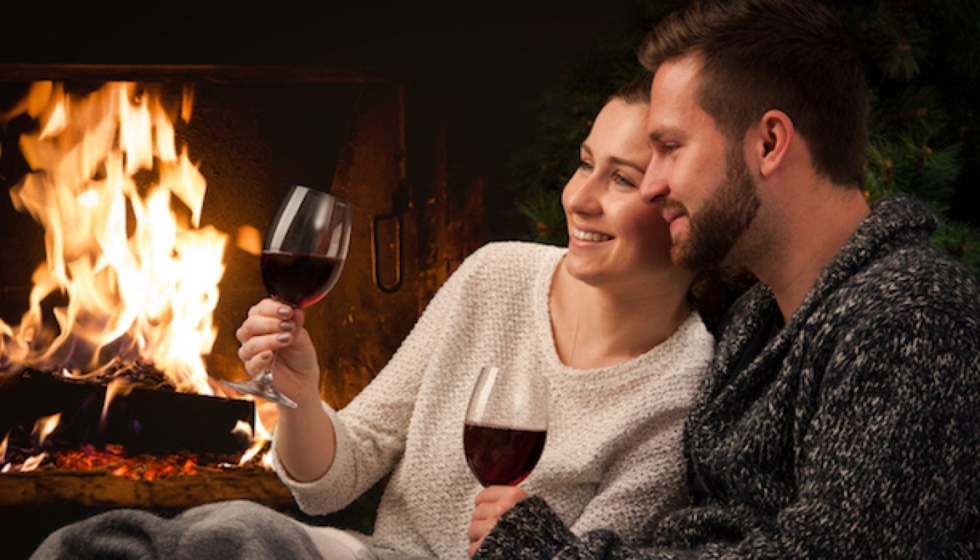 Couple with glass of wine at fireplace