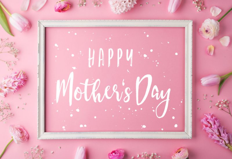 Mothers day composition. Happy mothers day text and flowers. Studio shot on a pink background. Flat lay.