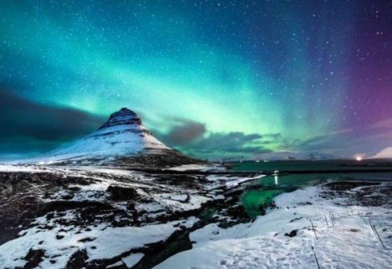 Northern lights in Mount Kirkjufell Iceland with a man passing by