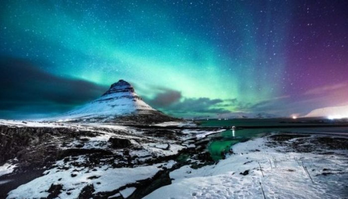 Northern lights in Mount Kirkjufell Iceland with a man passing by