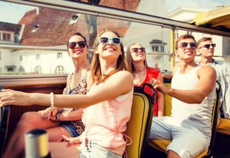 group of smiling friends traveling by tour bus